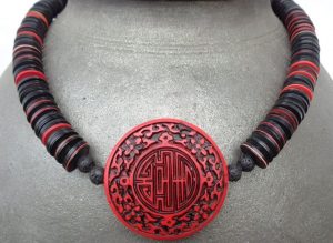 Traditionelle, chinesische Cinnabar – Scheibe. Sie hat einen Durchmesser von 5 cm und ist konvex. Das Zeichen in der Mitte bedeutet Freude, Glück. Ausserdem schwarze und rote Bakelit-Scheiben, ursprünglich aus Europa, jetzt aus Ghana