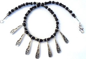 Halskette - 7 versilberte Anhänger mit einer Kokopelli-Darstellung, schamanisches Symbol der Anasazi im Südwesten der USA; schwarz-weiße kleine Handelsperlen aus Murano, Lava