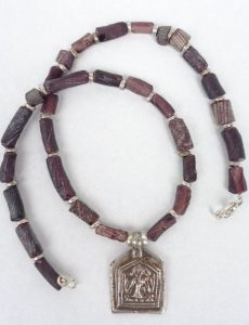 Halskette - Ein indisches Silber-Amulett hängt an einer Kette aus dunkel-violetten Glasröhrchen, die aus einer antiken römischen Glasmanufaktur in Bactria, heue in Afghanistan, stammen sollen